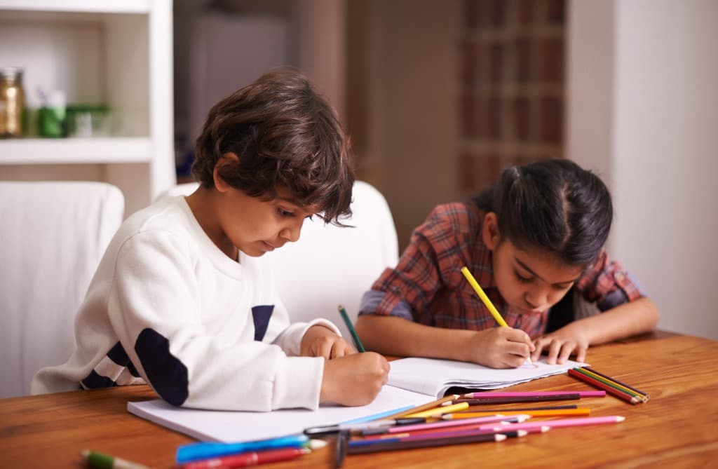 Two children drawing and learning together at a table
