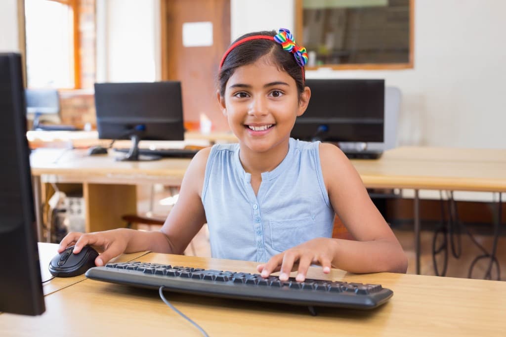 Student smiling while learning on a computer in class