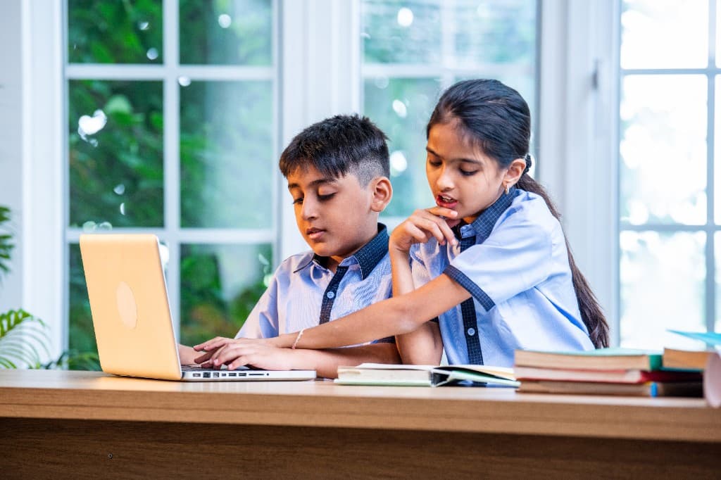 Students in school uniforms collaborating on a laptop